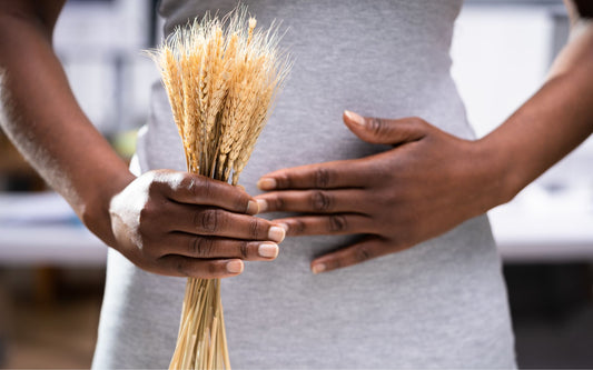 Person with hand on stomach and holding a wheat in other hand