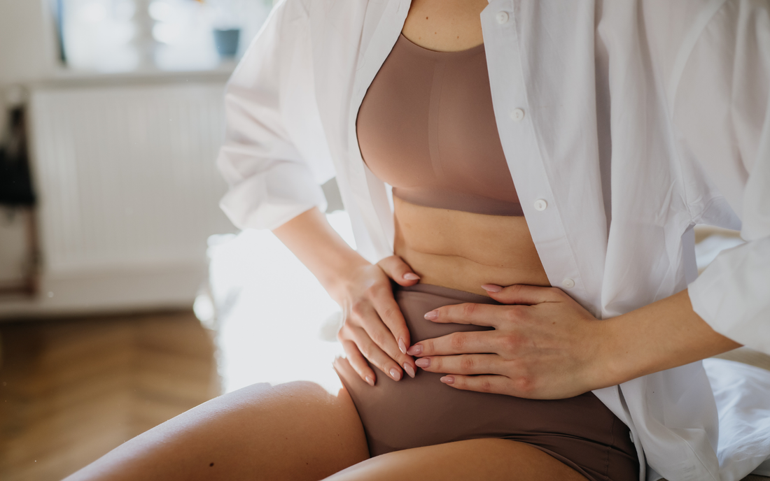 Woman sitting down with hands placed over her lower stomach